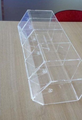 Contenitore multiscomparto in acrilico trasparente su un tavolo marrone chiaro.