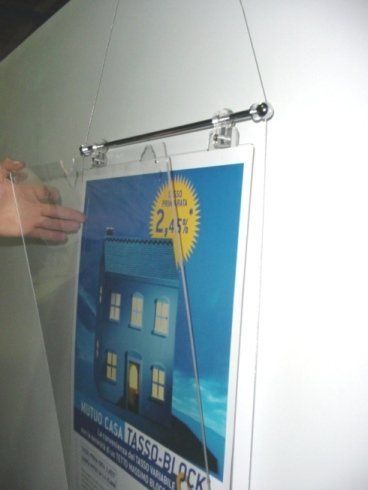 Un poster appeso a una parete bianca, fissato con plastica trasparente e un filo.