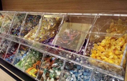 Esposizione di dolciumi con contenitori trasparenti pieni di caramelle colorate in un ambiente da negozio.