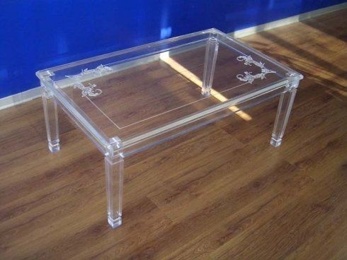 Tavolino da caffè rettangolare in acrilico trasparente su un pavimento in legno contro una parete blu.