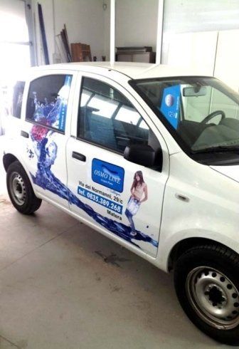 Auto bianca con grafica blu che pubblicizza il salone