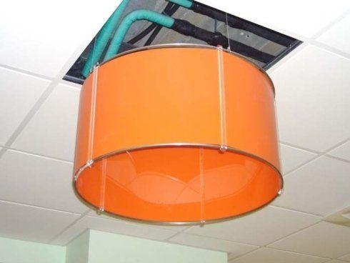 Diffusore d'aria cilindrico arancione appeso al soffitto, vicino ai condotti dell'aria.