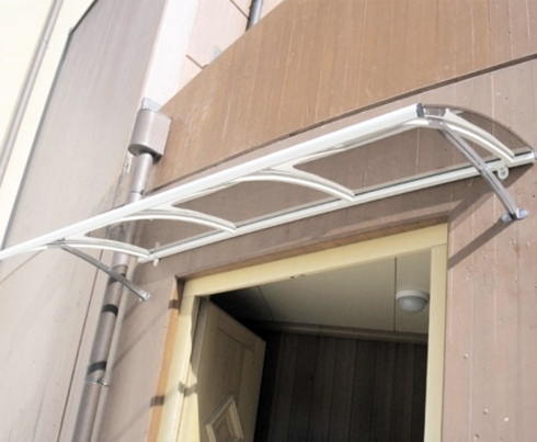 Tenda bianca sopra una porta, sullo sfondo di un edificio marrone.