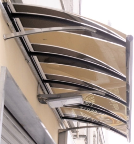 Tenda da sole color marrone chiaro e nero sopra la vetrina di un negozio, sostenuta da bracci in metallo argentato e da un lampadario.