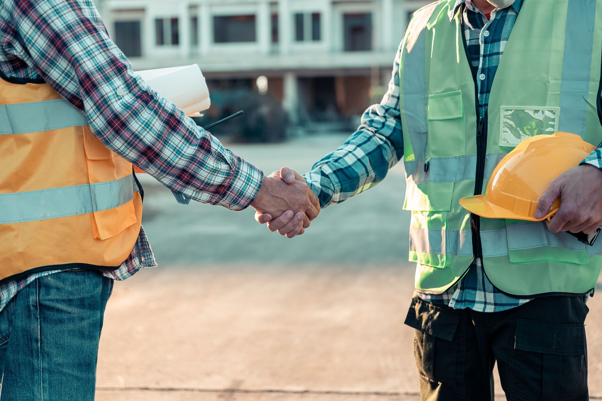 Due operai edili si stringono la mano in un cantiere.