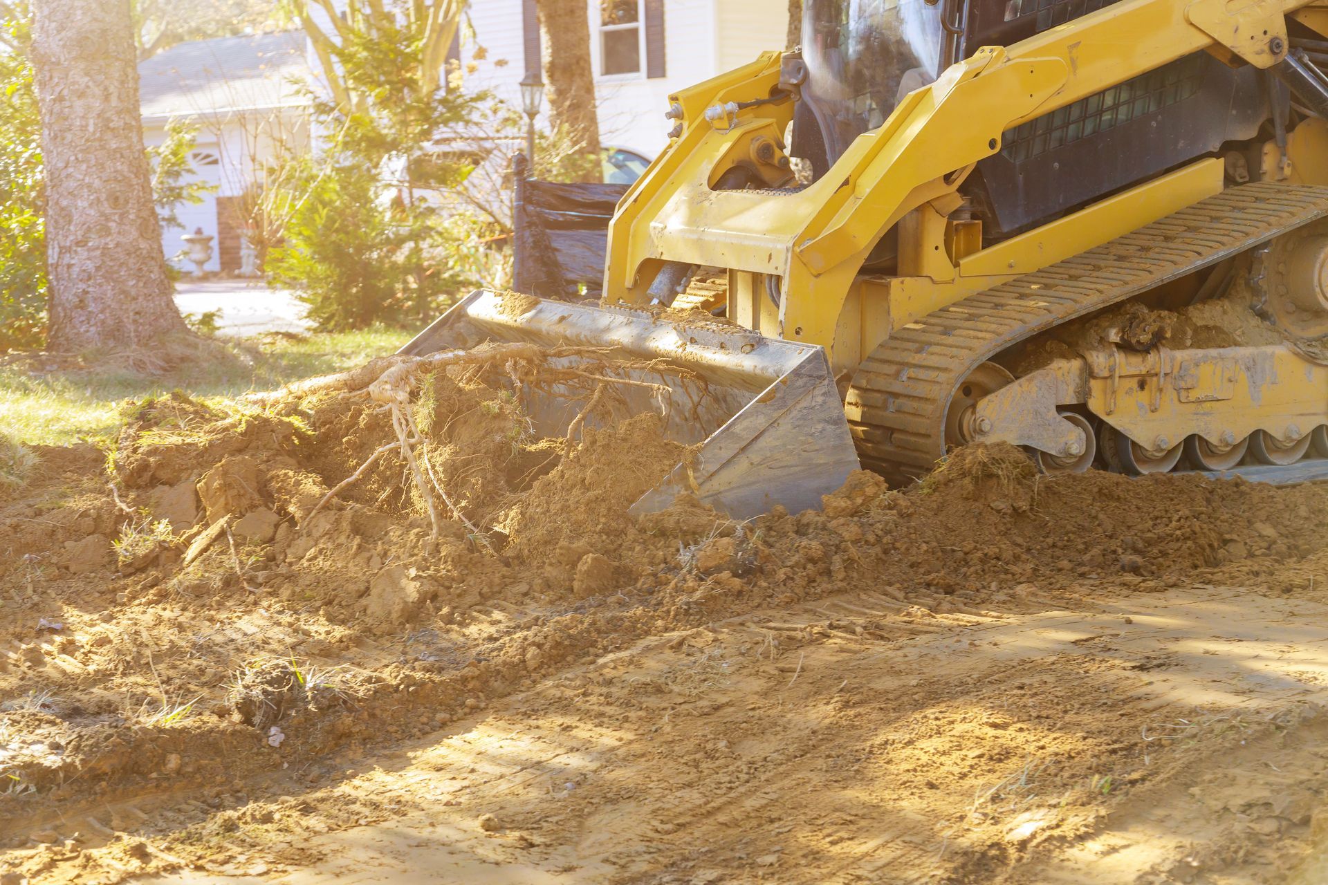 Un bulldozer creuse un trou dans la terre devant une maison.