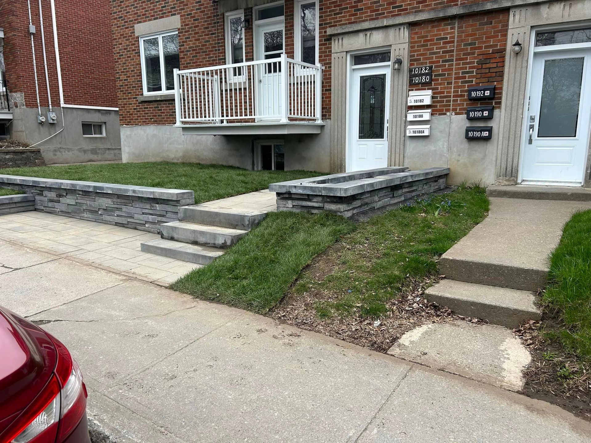 Une voiture rouge est garée devant un bâtiment en briques.