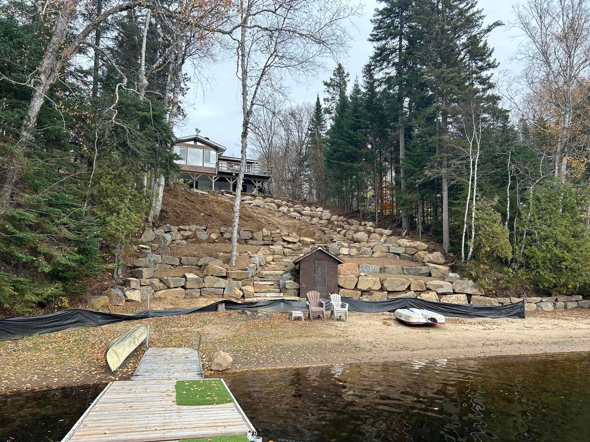 Une maison est assise au sommet d'une colline à côté d'un lac.