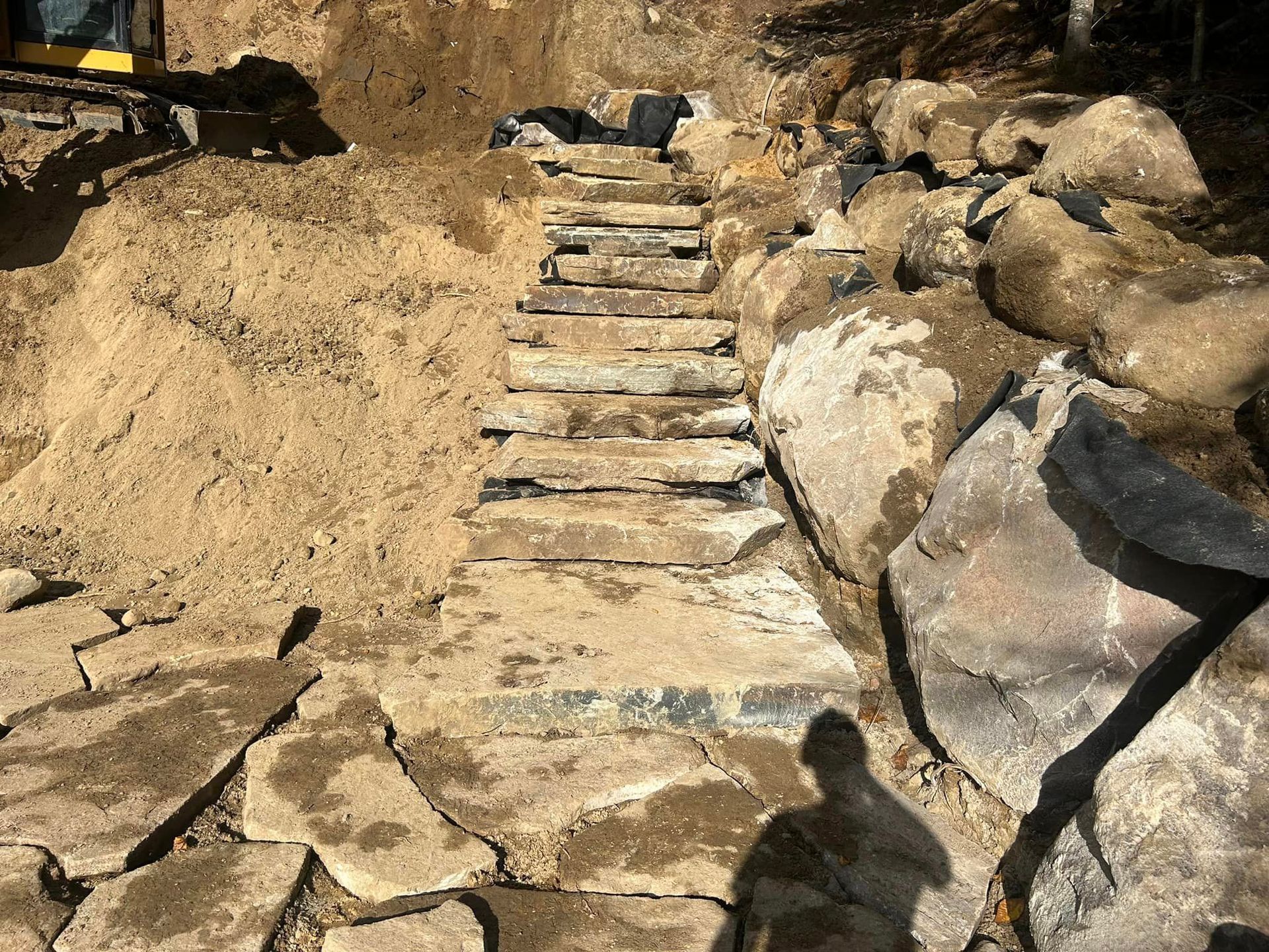 Un escalier est en train d'être construit dans la terre à côté d'un tas de rochers.
