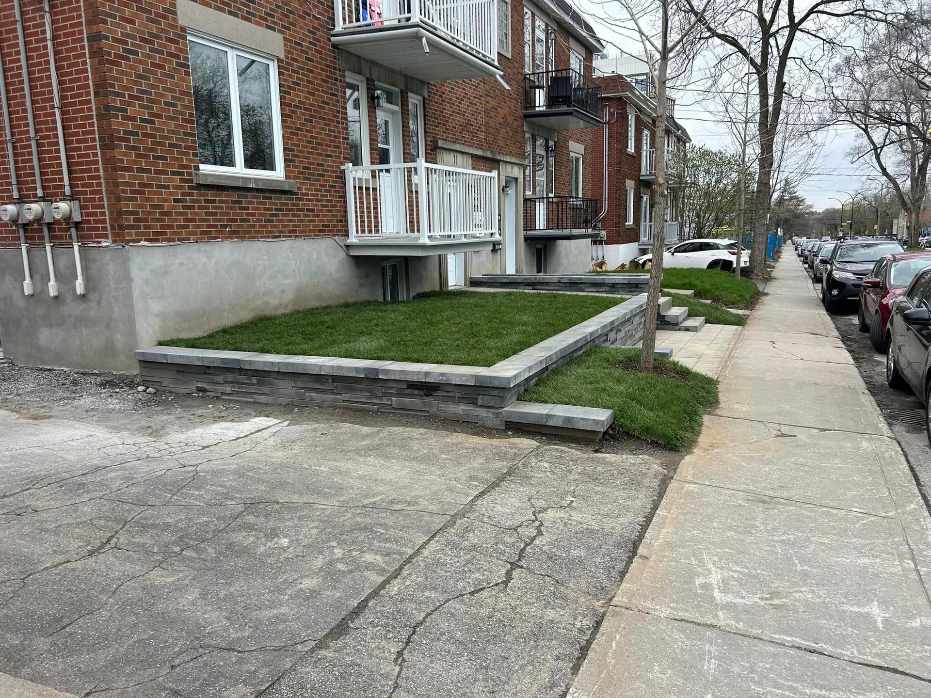Un trottoir à côté d'un bâtiment en briques avec une pelouse verte luxuriante.