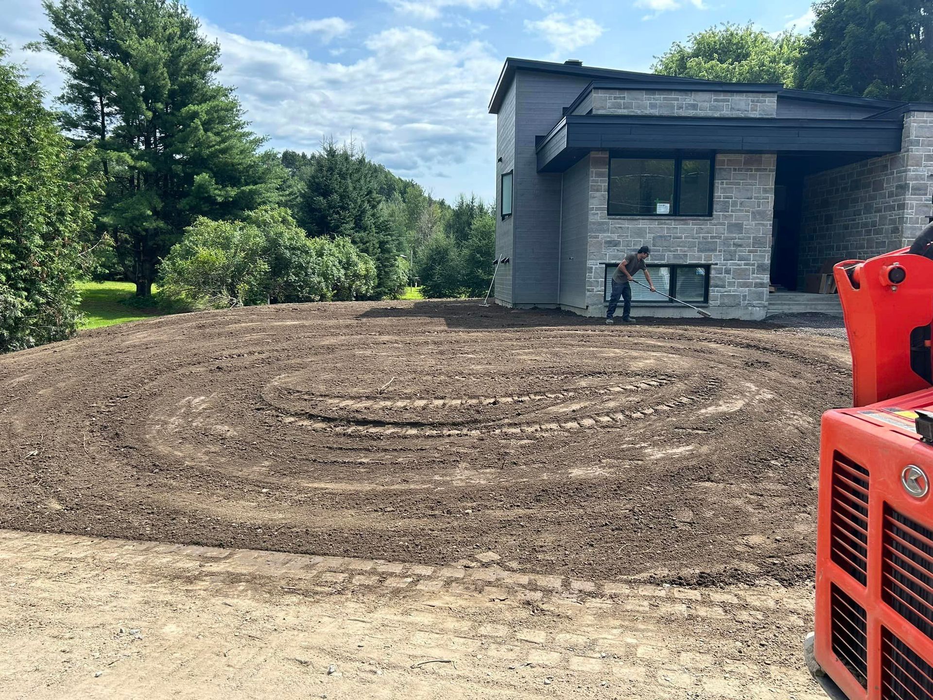Un homme se tient debout dans un labyrinthe de terre devant une maison.