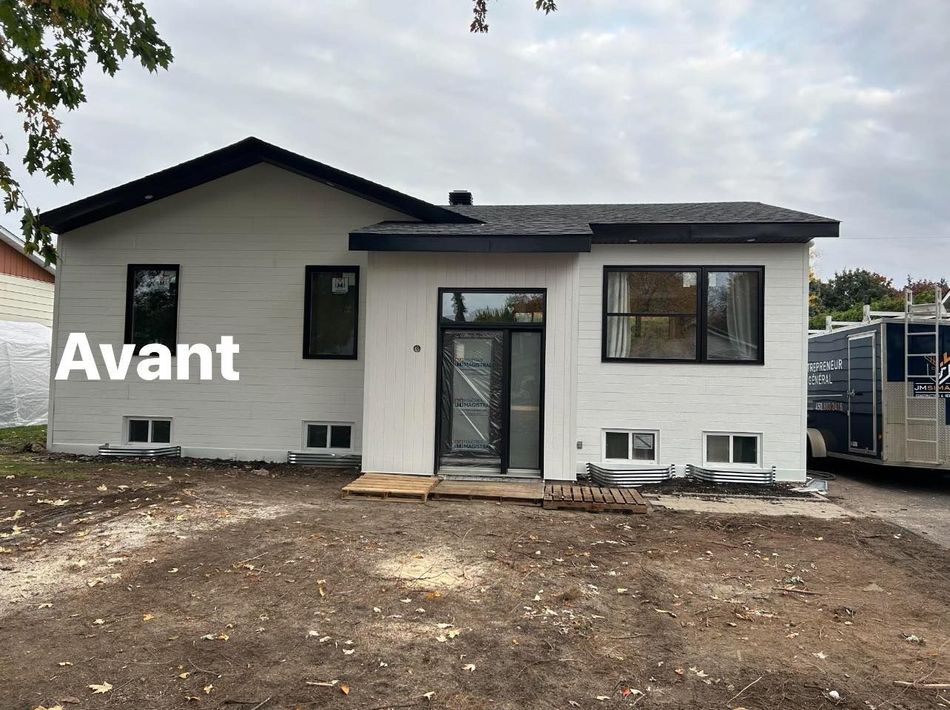 Une maison blanche avec un toit noir est en cours de rénovation.