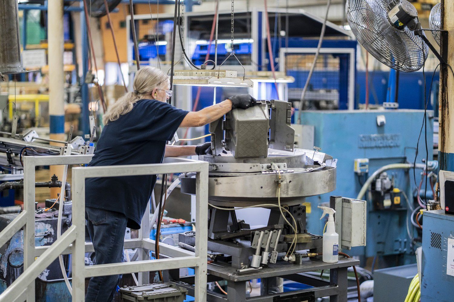 RIMA Manufacturing Company team member, working on a machine, wearing gloves.