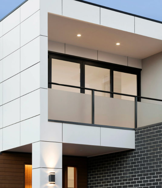 Modern two-story house with white paneling, black framed windows, and a brick facade.