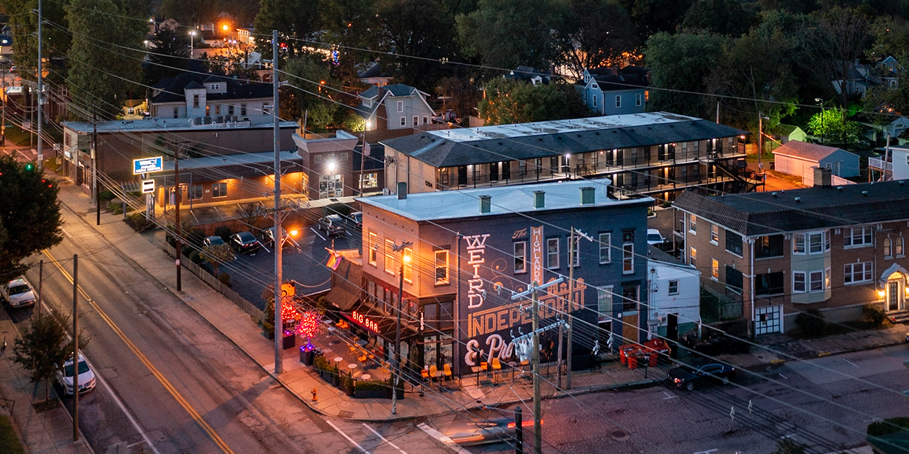 Aerial view of a city street at night with buildings, cars, and streetlights.