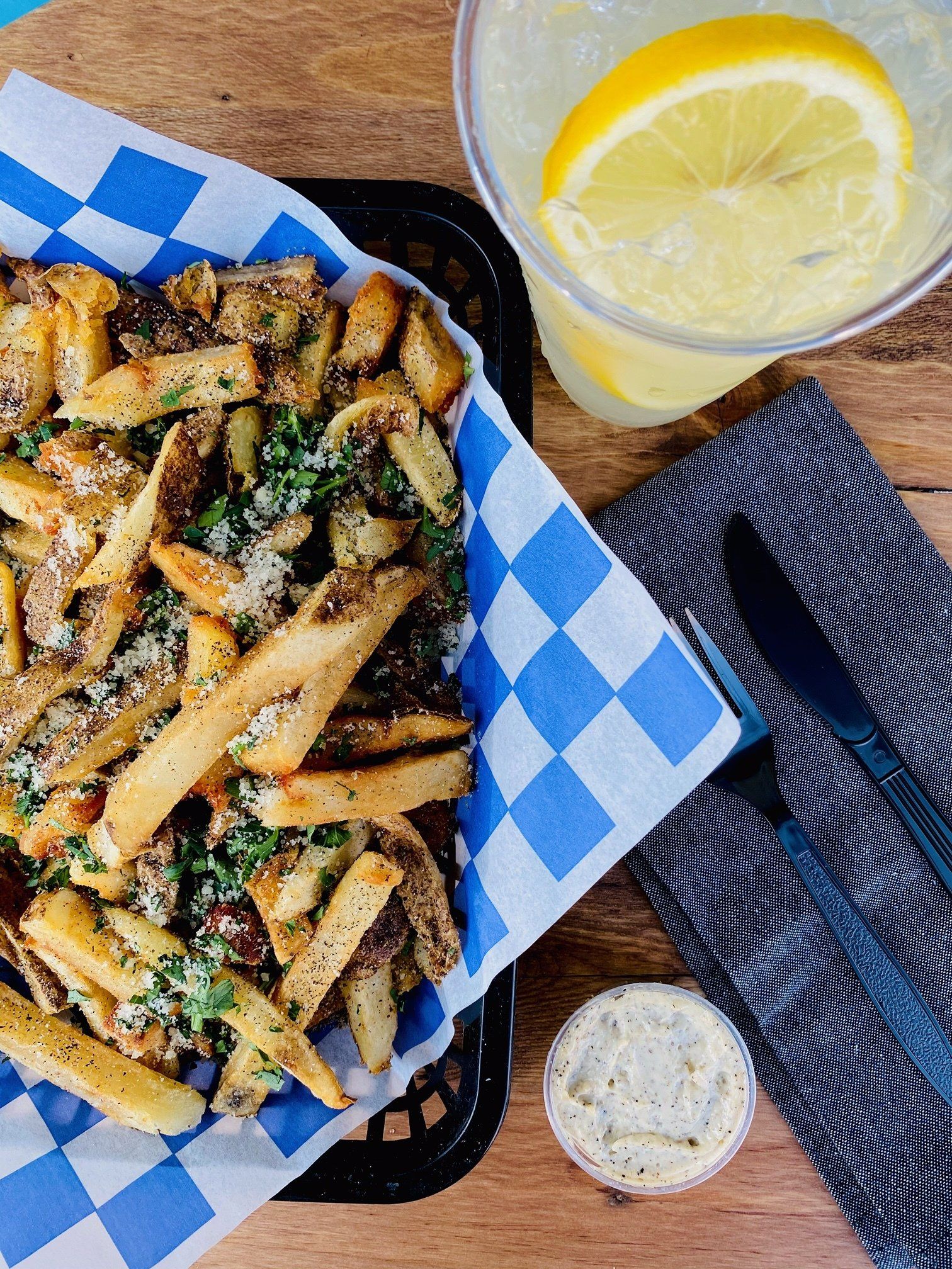 A basket of french fries and a glass of lemonade on a table.