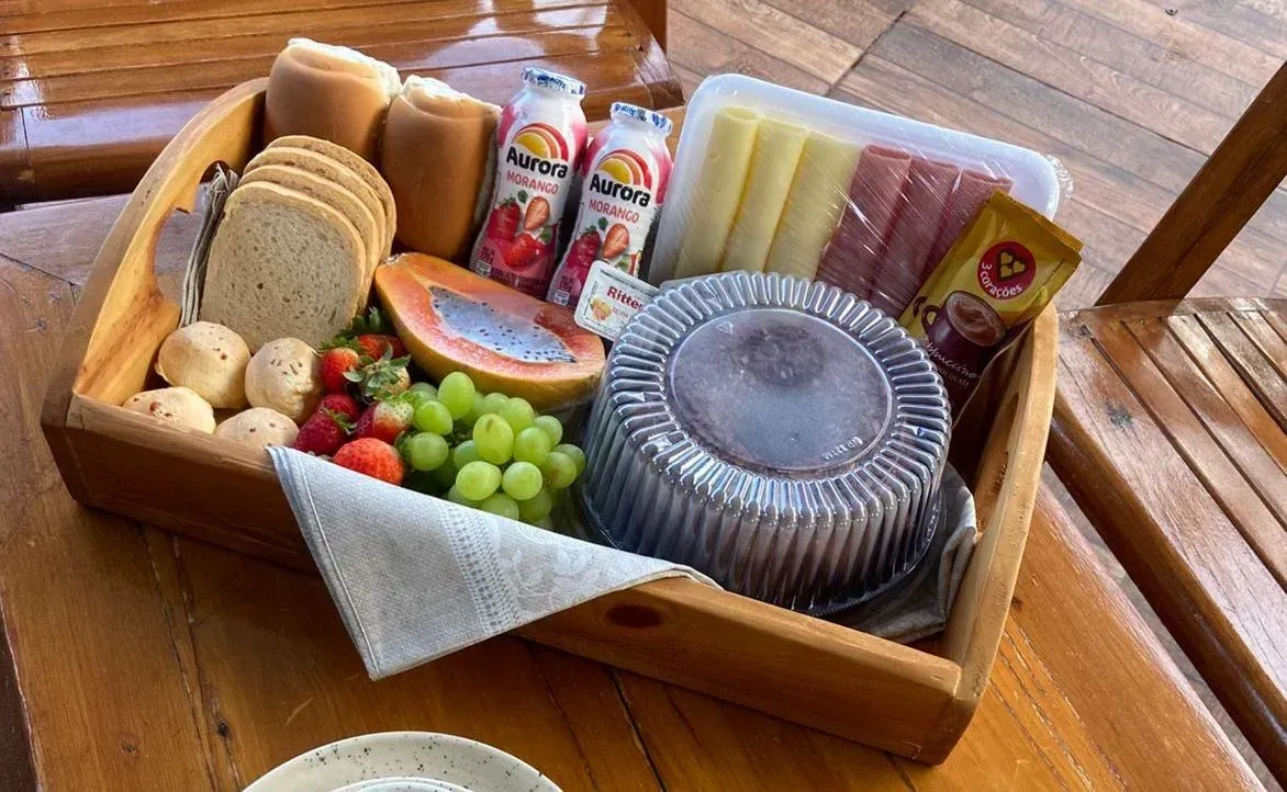 Bandeja de madeira com alimentos para o café da manhã, incluindo pão, frutas, iogurte, queijo e bolo
