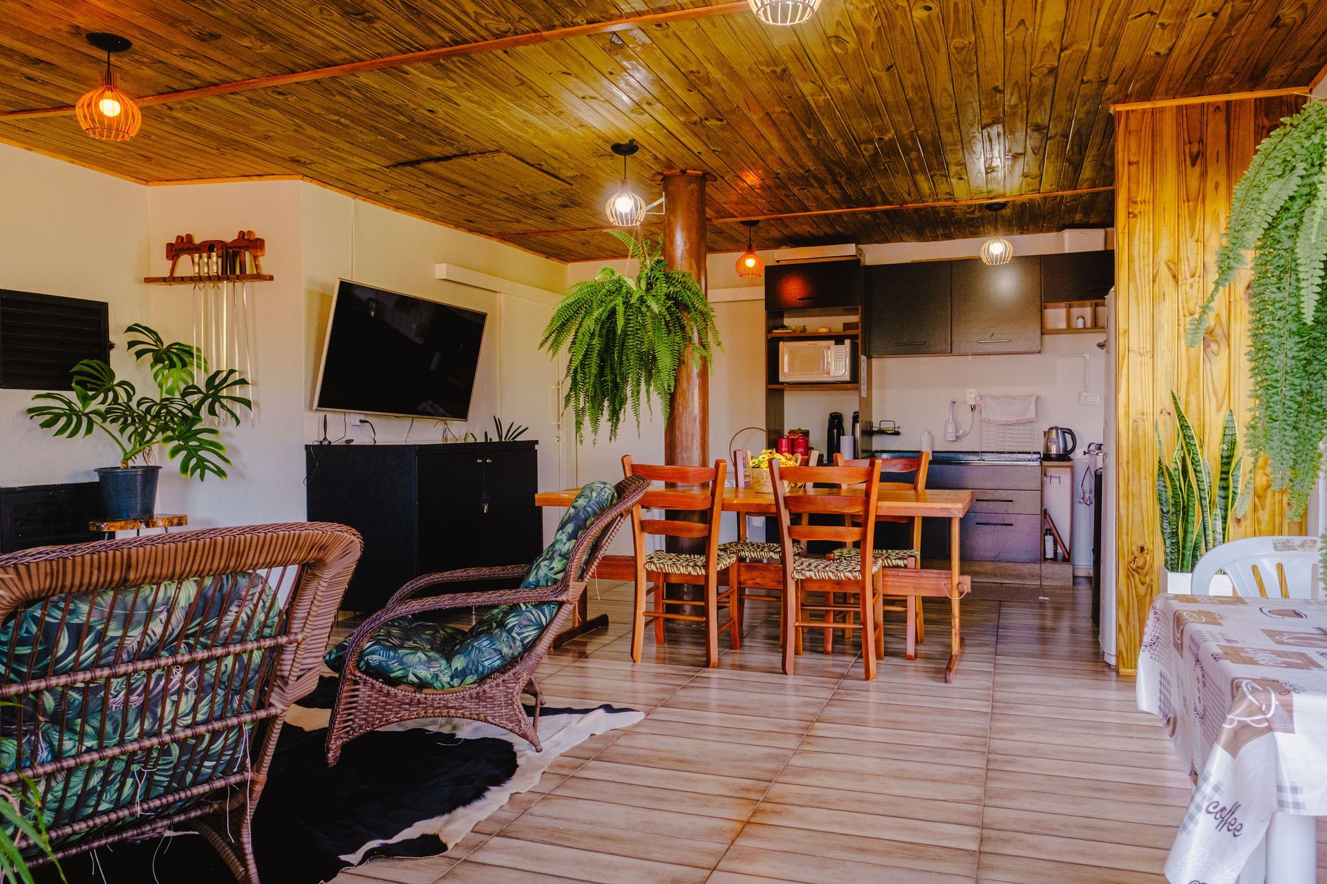 Interior aconchegante com teto de madeira, cozinha, mesa de jantar e áreas de estar.