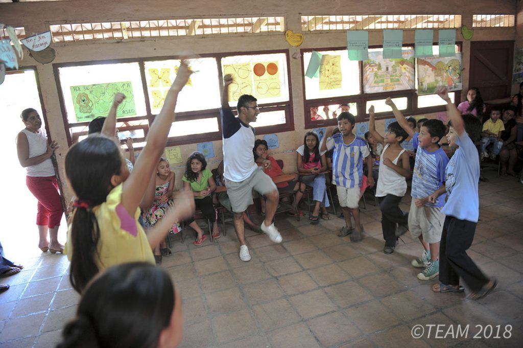 A camp leader dances with a group of kids at Vacation Bible School