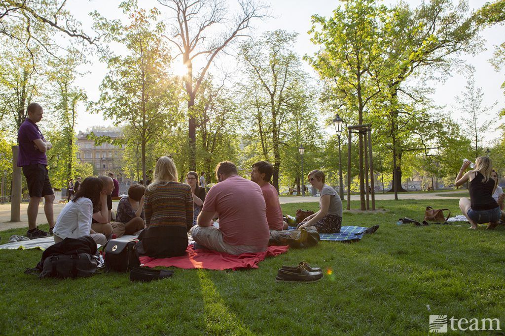 A group of people sit down together for a picnic dinner in the park.