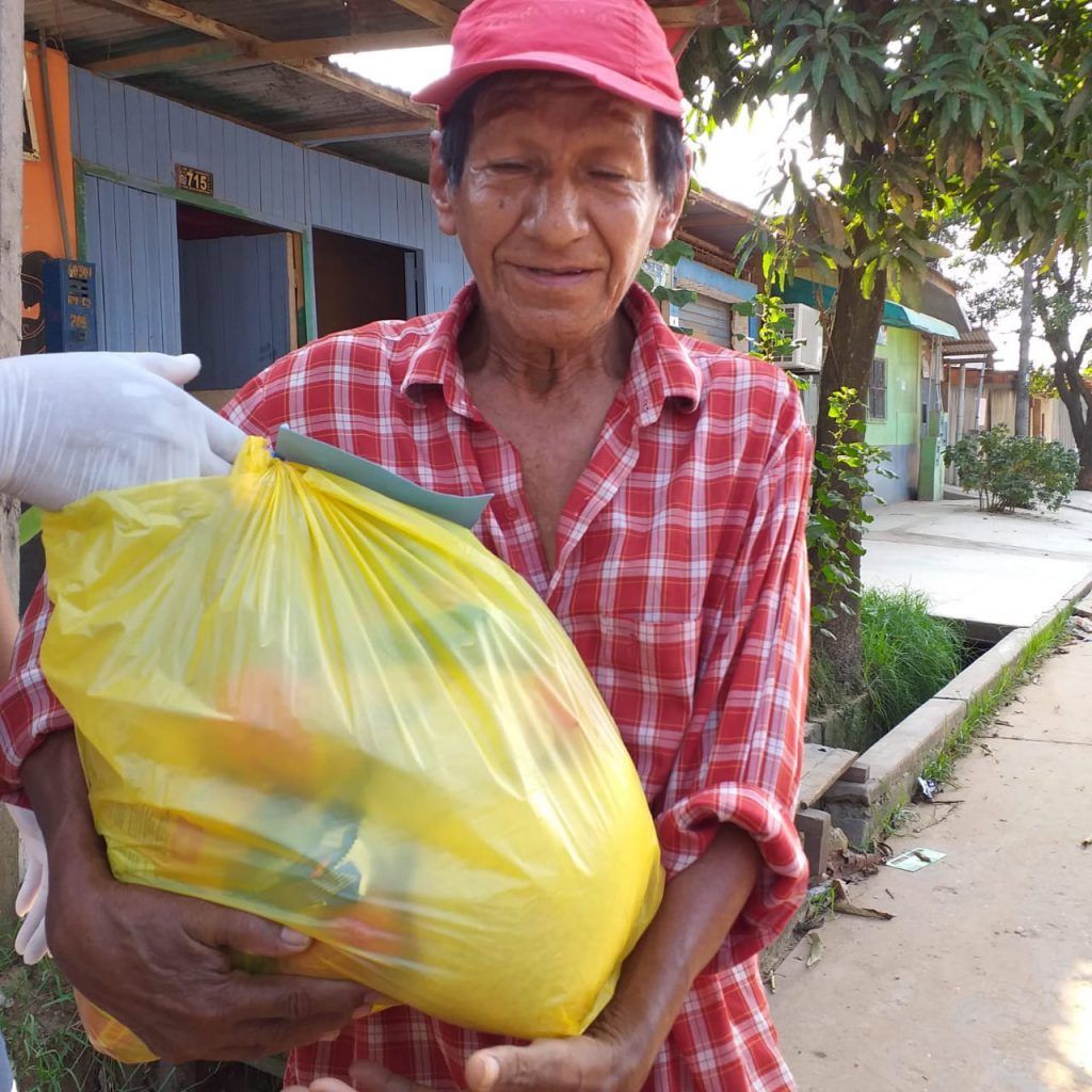 A man holds a large grocery bag he received as part of COVID-19 ministry