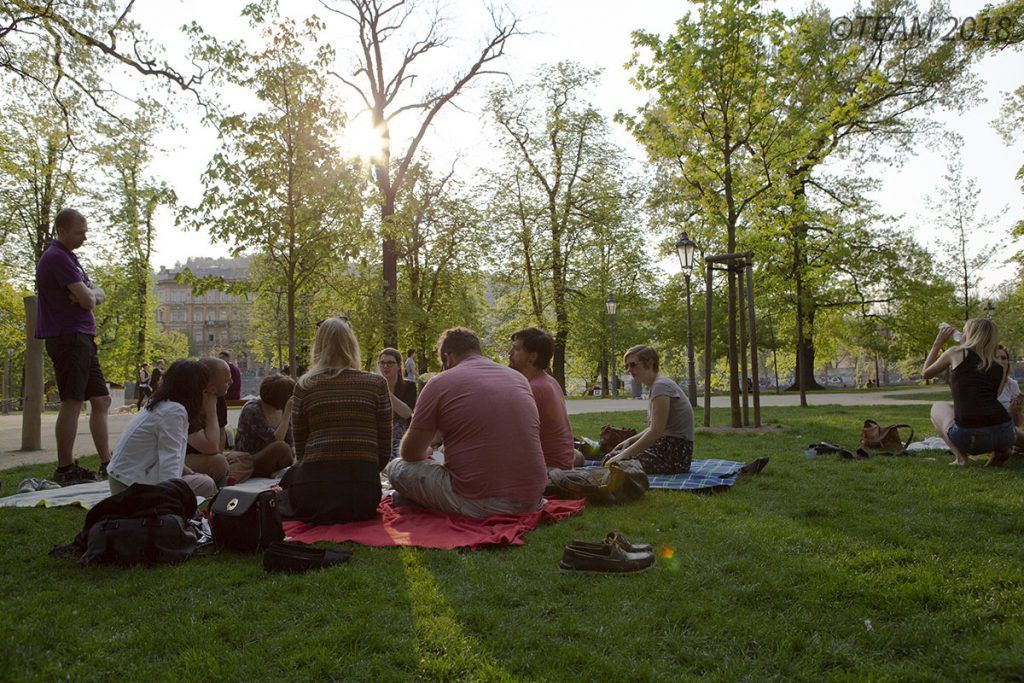 A group of missionaries sit on a blanket in the park to talk.