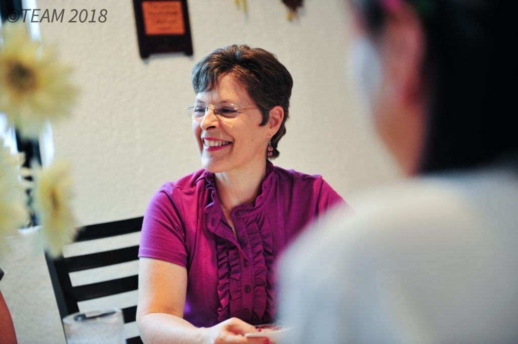 A missionary woman over 50 speaks with other people.