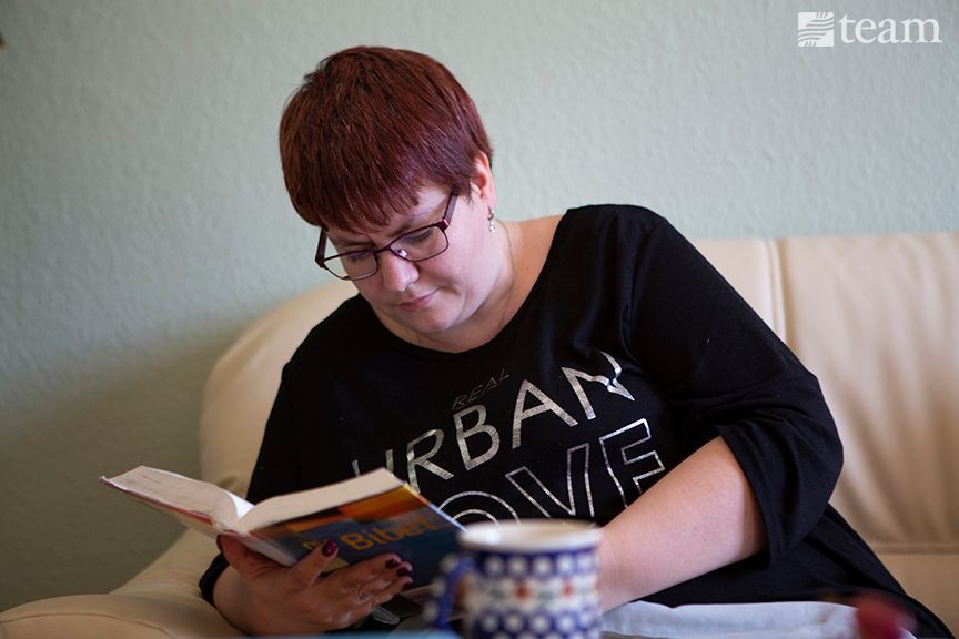 A woman in Germany, a post-Christian culture, reads the Bible on a couch