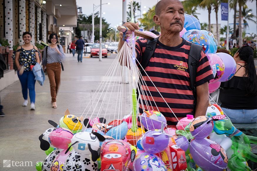 A man holds various children's' balloons for sale.