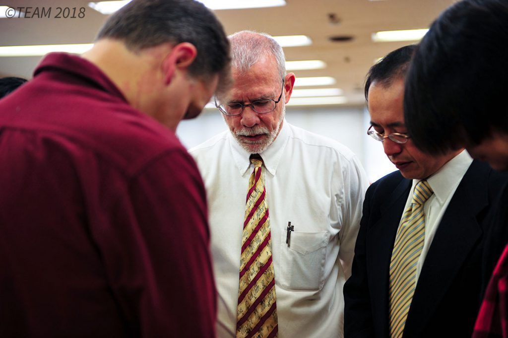 A group of men pray together.