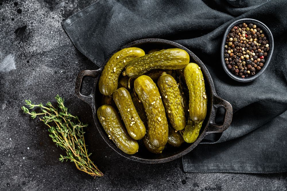 A bowl of pickles and a bowl of pepper on a table.