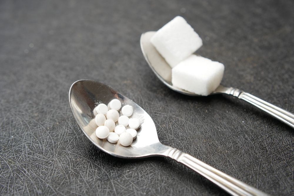 Two spoons filled with sugar cubes and pills