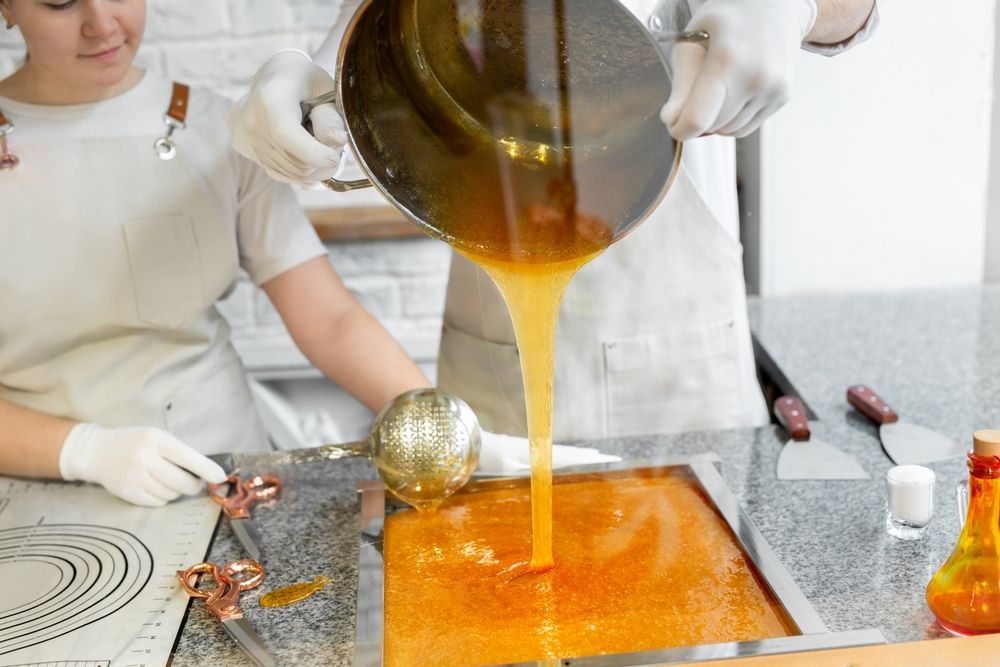 A woman is pouring liquid from a pot into a pan.