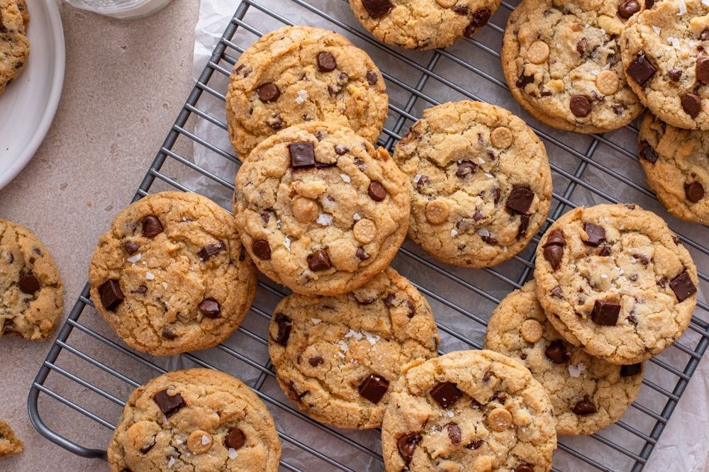 A bunch of chocolate chip cookies are sitting on a cooling rack.