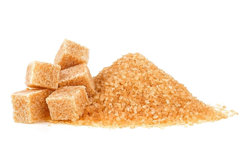 A pile of cane sugar next to a pile of cane sugar cubes on a white background.