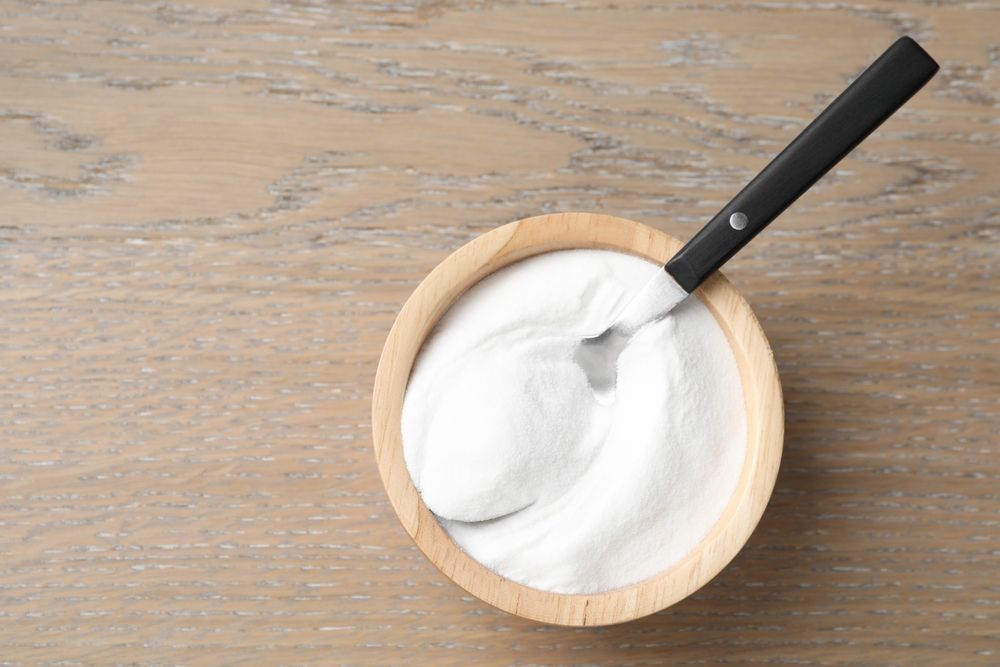 A bowl of sour cream with a spoon in it on a wooden table.