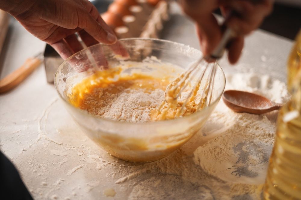 A person is mixing ingredients in a bowl with a whisk.