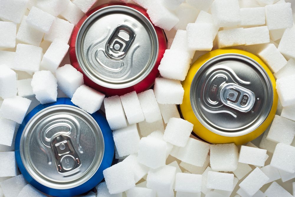 a blue, red, and yellow soft drink can surrounded by sugar cubes