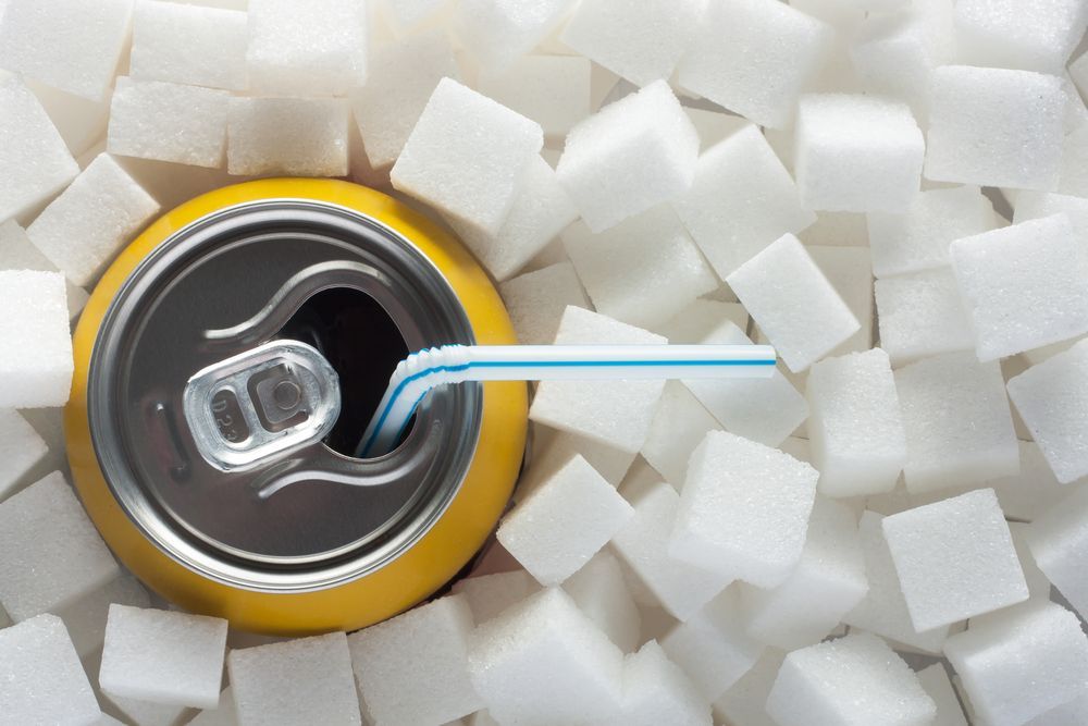a yellow unbranded can with a blue and white straw in it, surrounded by sugar cubes