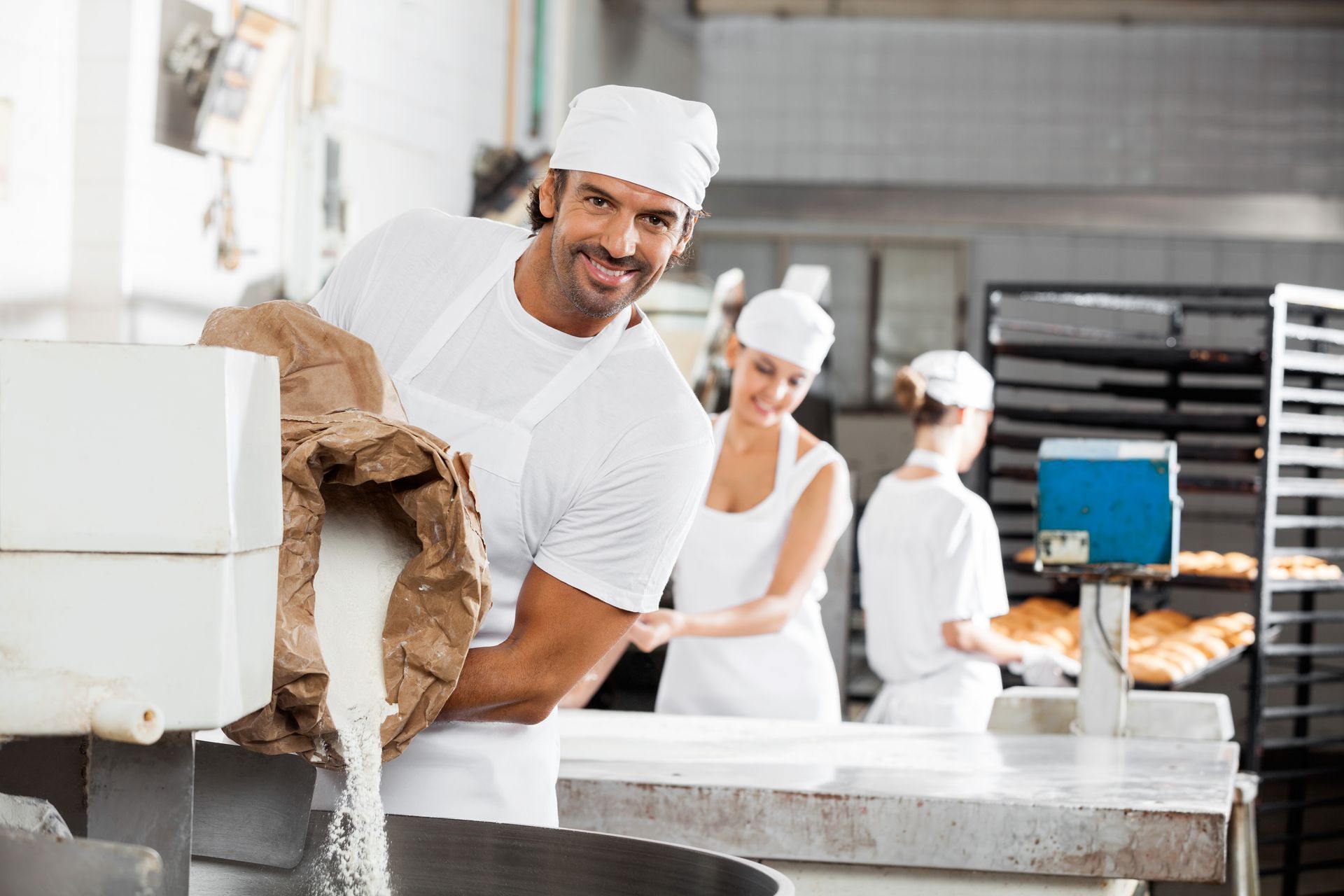 A pastry chef adding sugar into a large mixer, he knows techniques for long term storage of sugar