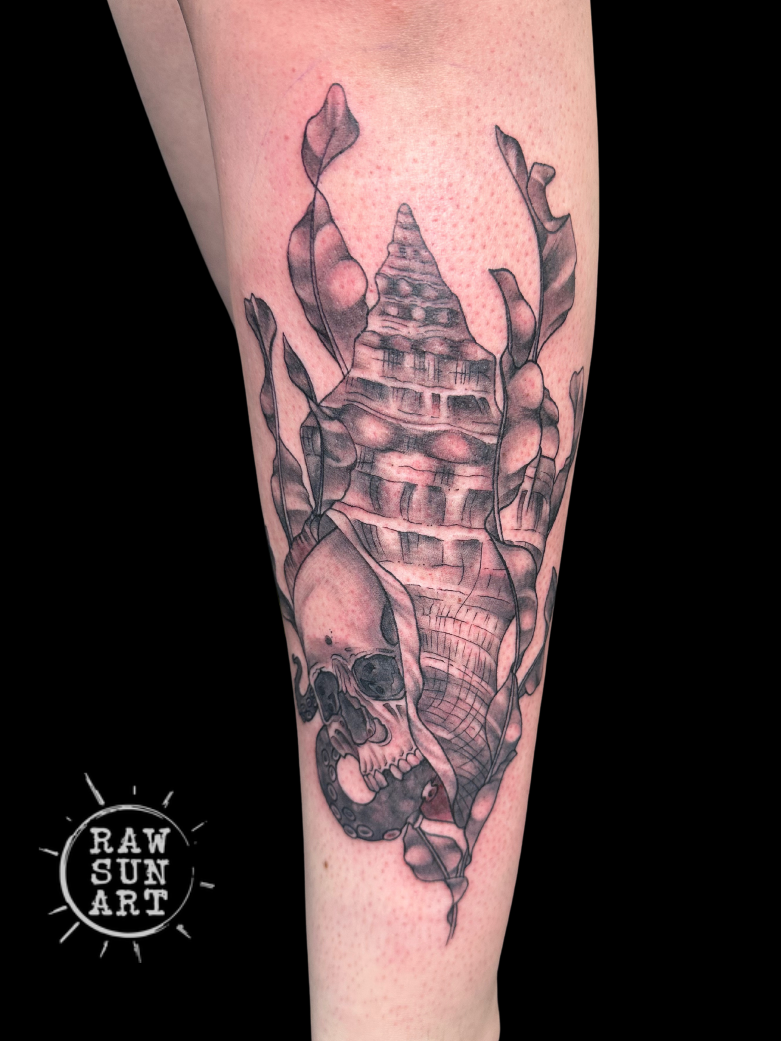 A black and white tattoo of a skull on a person 's leg.