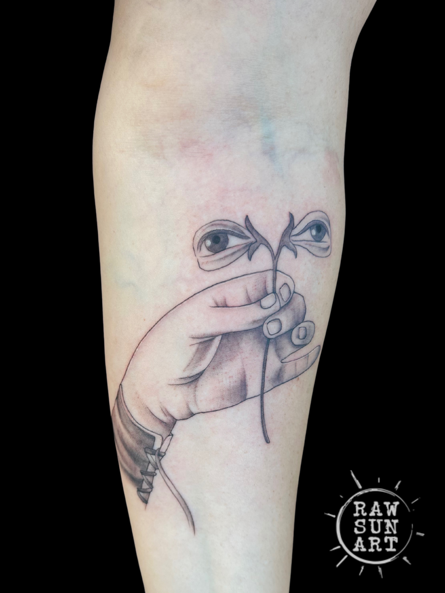 A black and white tattoo of a hand holding a plant