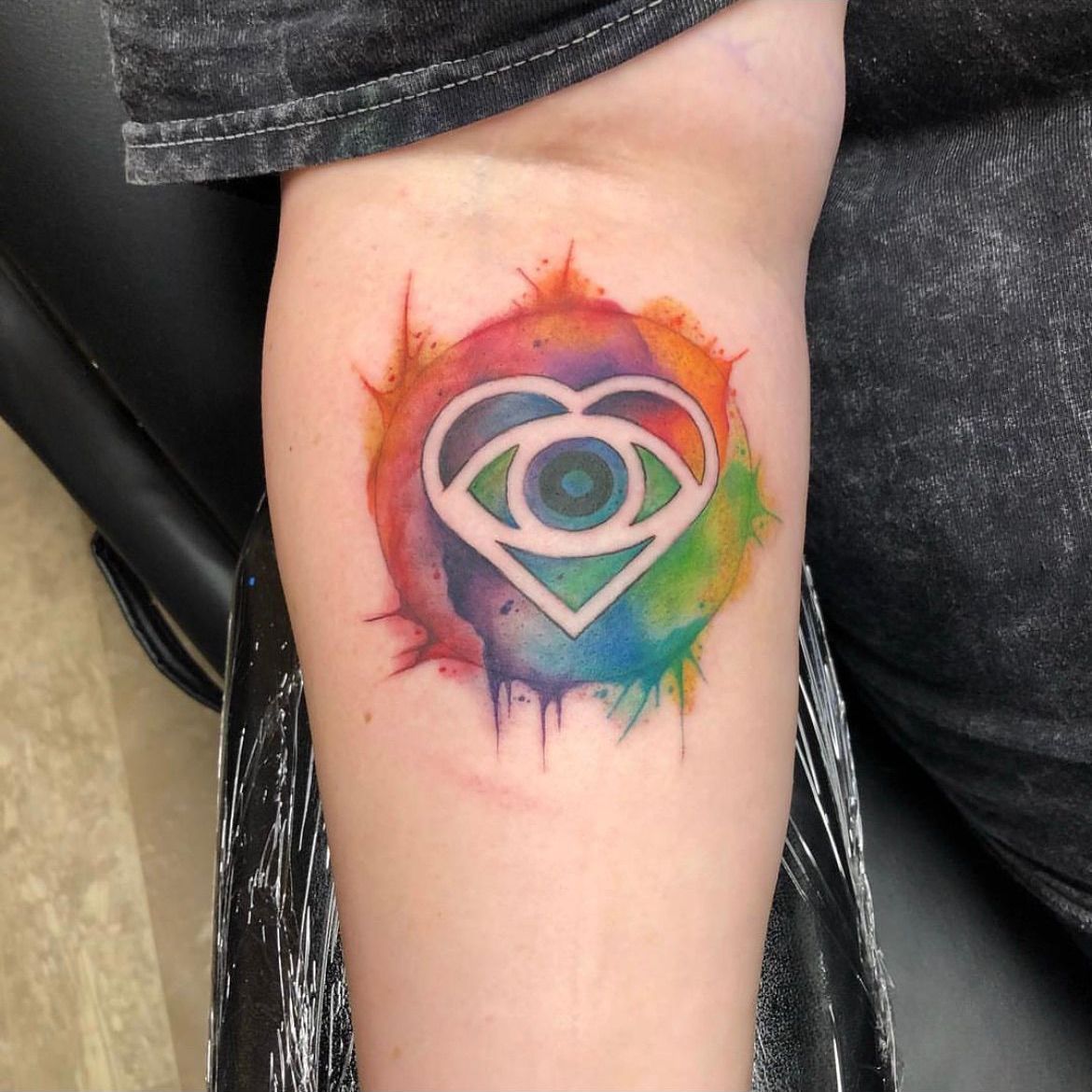 A person has a tattoo of an eye in a heart on their arm.