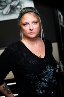 A woman with a tattoo on her arm is wearing a headband and a black shirt.