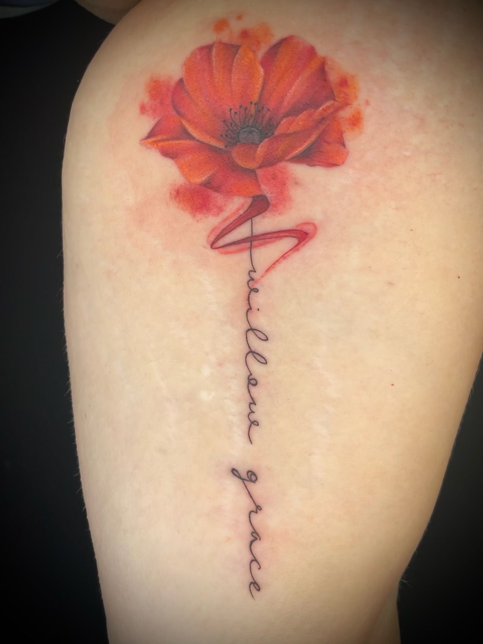 A woman has a tattoo of a red flower and the words william grace