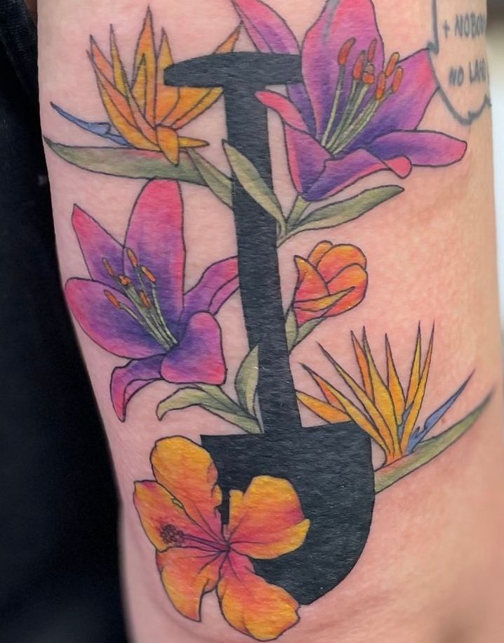 A person has a tattoo of flowers and the letter i