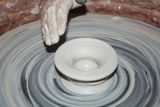 A person is making a vase on a pottery wheel