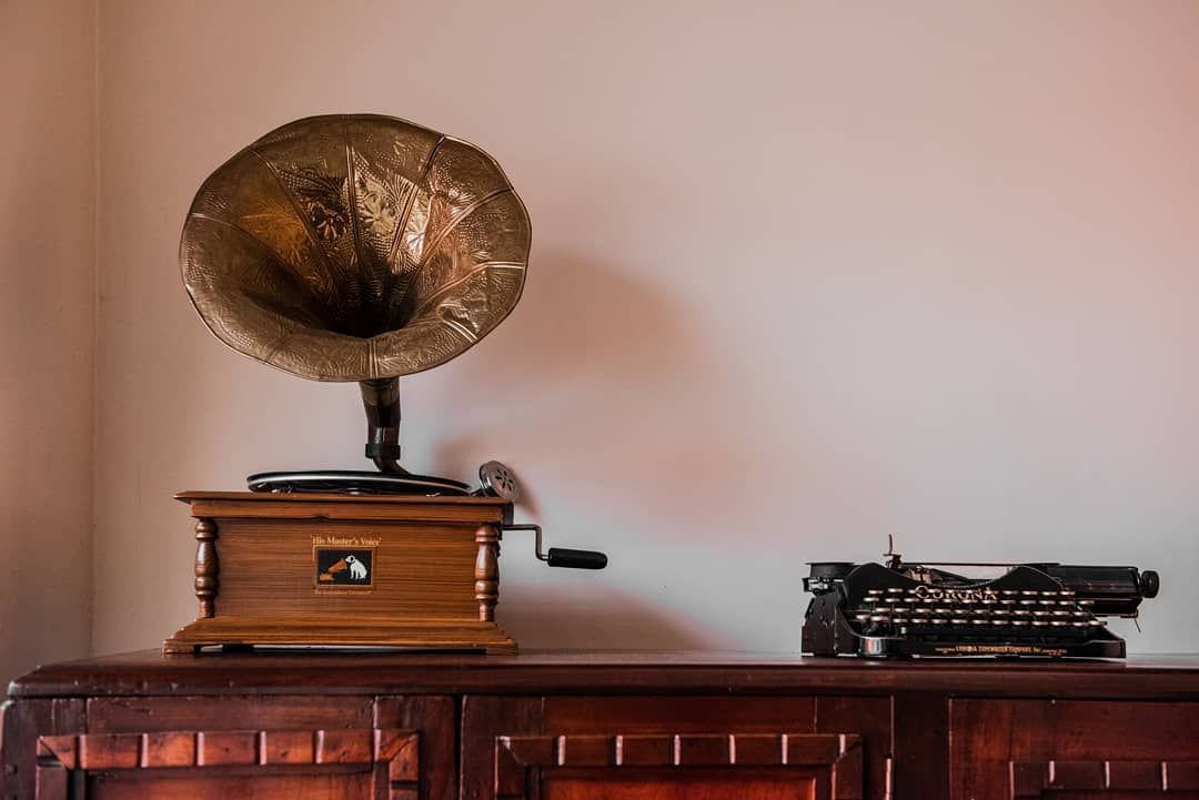Gramófono y máquina de escribir sobre un mueble antiguo que dan calidez a la entrada del hotel