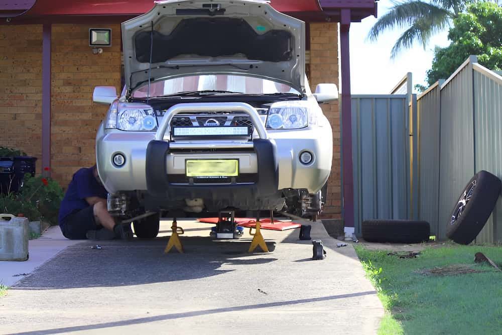 A Man Is Working On A Car With The Hood Up — Matthew Harding Mechanical Repairs In Urunga, NSW