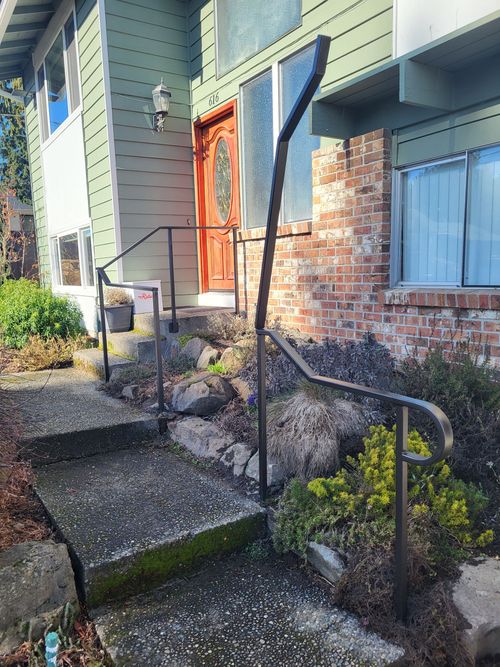 A house with stairs and a railing in front of it.